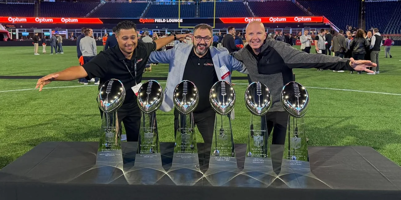 The Alphinity team behind six Lombardi trophies on the field at Gillette Stadium
